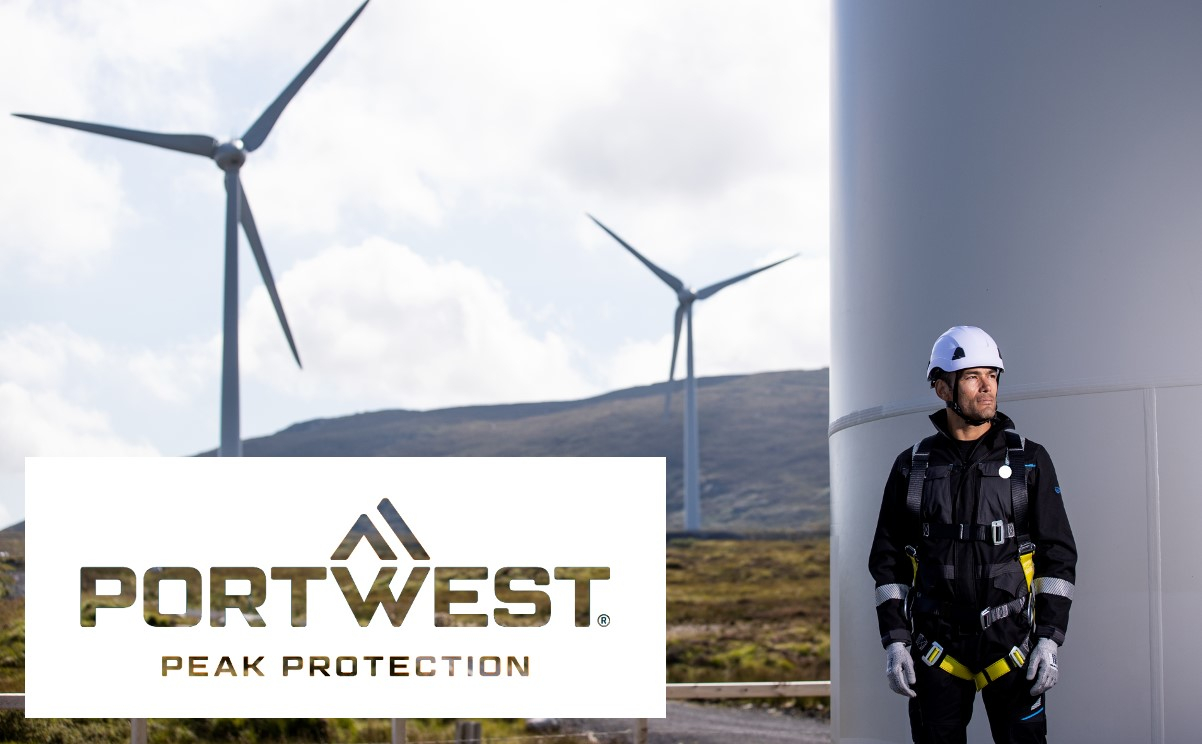 Een werknemer met volledige valbeschermingsuitrusting staat naast een windturbine. Op de achtergrond zijn nog meer windturbines te zien. Op de voorgrond is het bedrijfslogo van Portwest met de slogan 'Peak Protection' weergegeven. Er is een link aanwezig die naar onze valbeveiliging leidt.