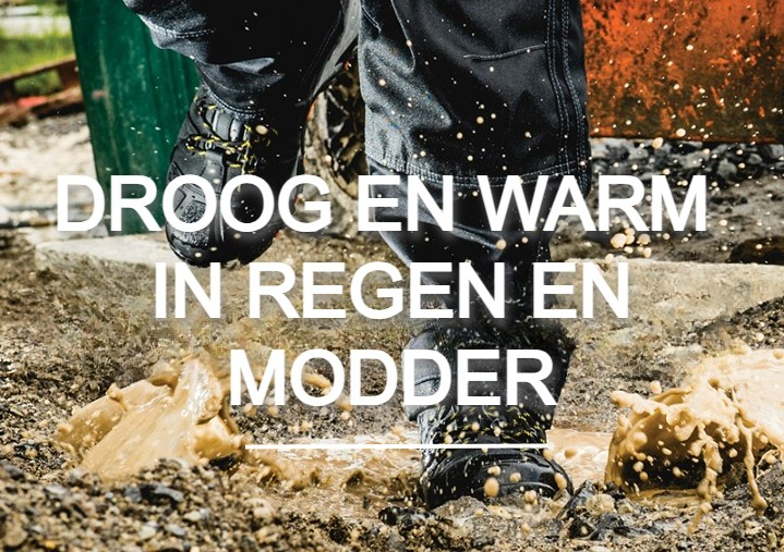 Werknemer in regenbroek en laarzen die in een plas loopt. Modder spat en op de achtergrond zie je een bouwplaats. Er is een link naar onze waterdichte schoenen.